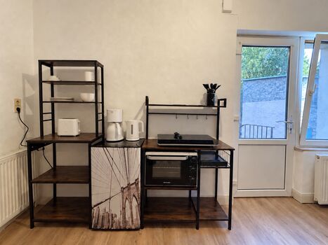 Kühlschrank, Kochgelegenheit mit Backofen und Regale sowie Eingangstür der Wohnung Kühlschrank, Kochgelegenheit mit Backofen und Regale sowie Eingangstür der Wohnung