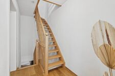 Zwei grüne Bouclé-Sessel um runden Holztisch, großes Frauenporträt als Wandkunst, hohe Zimmerpflanze Zwei grüne Bouclé-Sessel um runden Holztisch, großes Frauenporträt als Wandkunst, hohe Zimmerpflanze