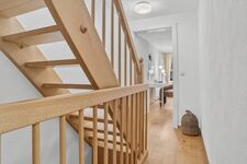 Helles Treppenhaus mit hellem Holzgeländer, Blick auf Flur und Schlafzimmer im Hintergrund. Helles Treppenhaus mit hellem Holzgeländer, Blick auf Flur und Schlafzimmer im Hintergrund.