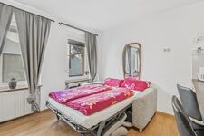 Helles Zimmer mit ausgeklapptem Schlafsofa, pinker Bettwäsche und grauem Vorhang. Helles Zimmer mit ausgeklapptem Schlafsofa, pinker Bettwäsche und grauem Vorhang.