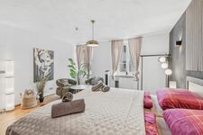 Sitzecke mit zwei grünen Polstersesseln, Hängeleuchte, Wandbild und üppiger Zimmerpflanze. Sitzecke mit zwei grünen Polstersesseln, Hängeleuchte, Wandbild und üppiger Zimmerpflanze.