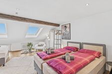 Helles Dachzimmer mit Dachflächenfenster, Einzelbett mit pinker Bettwäsche und Vintage-Regal. Helles Dachzimmer mit Dachflächenfenster, Einzelbett mit pinker Bettwäsche und Vintage-Regal.