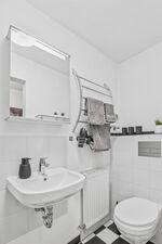 Weißes Badezimmer mit Waschtisch, Spiegel mit Beleuchtung und gefalteten Handtüchern. Weißes Badezimmer mit Waschtisch, Spiegel mit Beleuchtung und gefalteten Handtüchern.