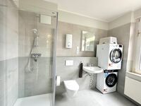 Badezimmer mit Dusche, Waschmaschine und Trockner Badezimmer mit Dusche, Waschmaschine und Trockner