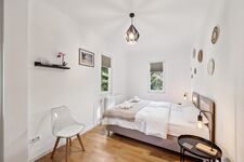 Schlafzimmer 1 mit hochwertigen Boxspringbetten, Nachttischen und einem offenen Kleiderschrank sowie Blick ins Grüne. Die Betten können wahlweise einzeln oder als komfortables Doppelbett gestellt werden. Schlafzimmer 1 mit hochwertigen Boxspringbetten, Nachttischen und einem offenen Kleiderschrank sowie Blick ins Grüne. Die Betten können wahlweise einzeln oder als komfortables Doppelbett gestellt werden.