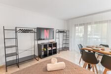 Helles Wohn- und Esszimmer mit 55 Zoll Smart-TV. Offene Kleiderständer und Regale bieten ausreichend Stauraum für längere Aufenthalte. Viel Tageslicht durch große Fensterfront. Helles Wohn- und Esszimmer mit 55 Zoll Smart-TV. Offene Kleiderständer und Regale bieten ausreichend Stauraum für längere Aufenthalte. Viel Tageslicht durch große Fensterfront.