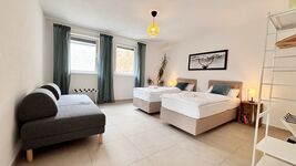 Modernes Doppelzimmer mit zwei Einzelbetten, Schlafsofa und stilvoller Einrichtung. Helle Atmosphäre durch große Fenster, gemütliche Beleuchtung und dekorative Akzente – ideal für entspannte Aufenthalte. Modernes Doppelzimmer mit zwei Einzelbetten, Schlafsofa und stilvoller Einrichtung. Helle Atmosphäre durch große Fenster, gemütliche Beleuchtung und dekorative Akzente – ideal für entspannte Aufenthalte.