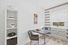 Quadratischer grauer Tisch mit zwei Stühlen, heller Raum mit Zimmerpflanze im Hintergrund. Quadratischer grauer Tisch mit zwei Stühlen, heller Raum mit Zimmerpflanze im Hintergrund.