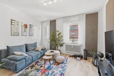 Blaues Sofa, bunter Teppich, runde Couchtische, große Zimmerpflanze, Fenster mit Blick auf Nachbarge Blaues Sofa, bunter Teppich, runde Couchtische, große Zimmerpflanze, Fenster mit Blick auf Nachbarge