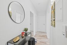 Weißes Bad mit rundem Wandspiegel, schwarzem Waschtisch, Kunstwerk an der Wand, heller Holzboden. Weißes Bad mit rundem Wandspiegel, schwarzem Waschtisch, Kunstwerk an der Wand, heller Holzboden.