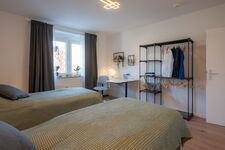 Schlafzimmer 1 mit zwei getrennten Betten (optional), Garderobe und Schreibtisch