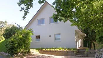 Frontansicht Haus mit dem Parkplatz im Vordergrund