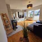 Großzügiges, helles Wohnzimmer der Dachgeschosswohnung mit Smart-TV und Zugang zum Balkon.