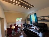 Modernes Premium Wohnzimmer mit Essbereich großem Sofa und PS5