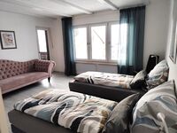 Zweibettzimmer mit Couch und Zugang zum Balkon