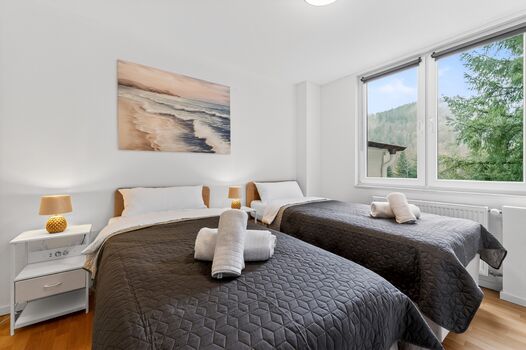 Schlafzimmer 1: Schlafzimmer mit hochwertigen Boxspringbetten, Nachttischen, offenem Kleiderschrank und Smart-TV. Die Betten können flexibel als Einzelbetten oder als komfortables Doppelbett gestellt werden.