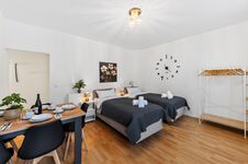 Wohnung 1: Wohnzimmer mit hochwertigen Boxspringbetten, Nachttischen, offenem Kleiderschrank und Smart-TV. Die Betten können flexibel als Einzelbetten oder als komfortables Doppelbett gestellt werden.