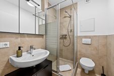 Wohnung 1: Modernes Badezimmer mit Dusche, Waschbecken und WC.