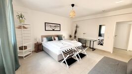 Modernes Doppelzimmer mit zwei Einzelbetten, zusätzliches Schlafsofa und stilvoller Einrichtung. Helle Atmosphäre durch große Fenster, gemütliche Beleuchtung und Schreibtisch