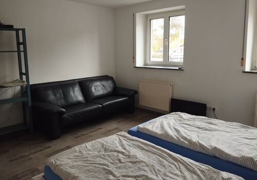 Merhbettzimmer mit Doppelbett und Couch