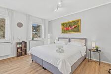 Zwei Einzelbetten zusammengestellt, großes Fenster mit Grünblick, buntes Moosgbild, heller Holzboden